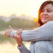 A lady outdoors stretching her left arm.