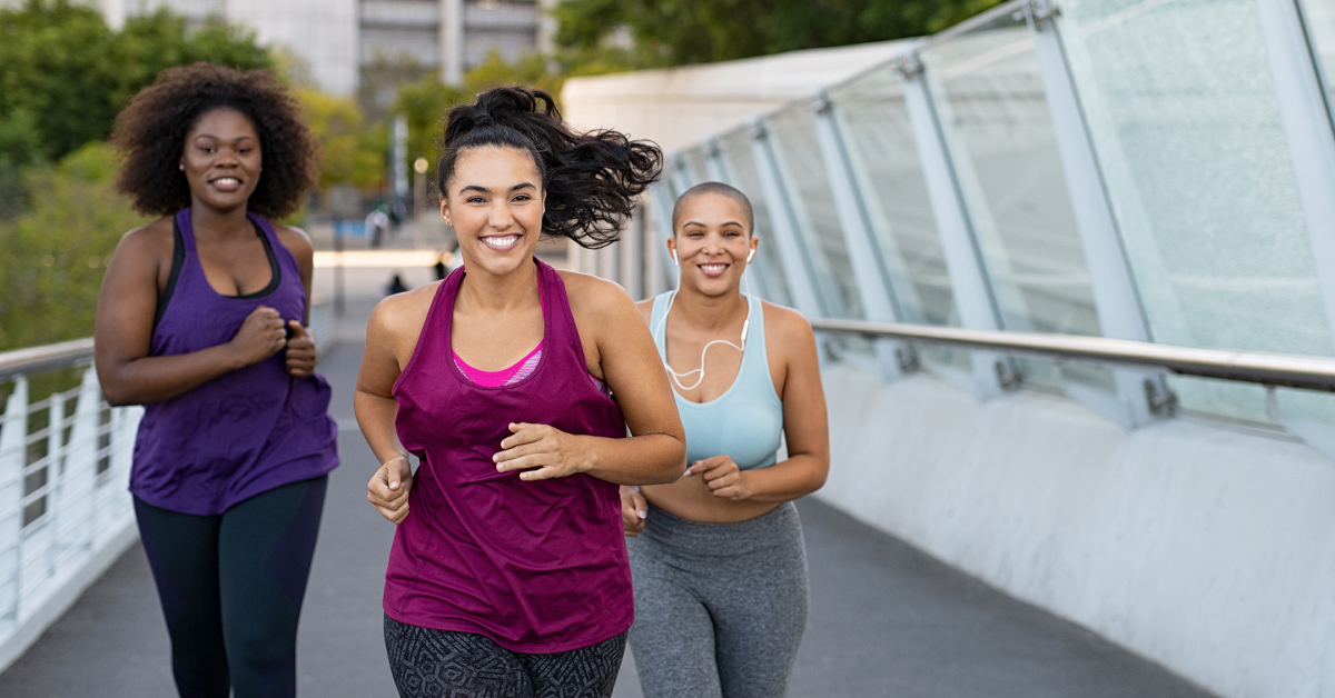 Three young women exercising by running in the city.