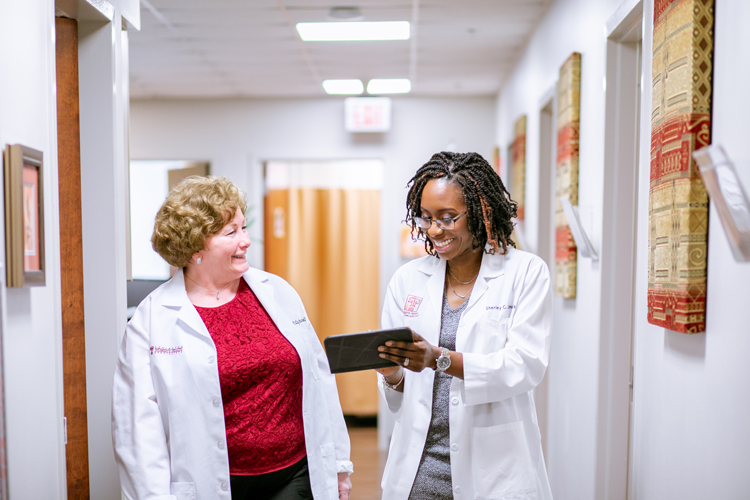 Two physicians of Covington Women's Health Specialists, talkig and smiling in the office's hallway.