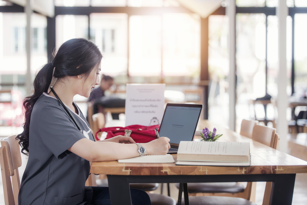 Concentrated doctor or nurse working on line with a laptop sitting in a desk in a consultation.