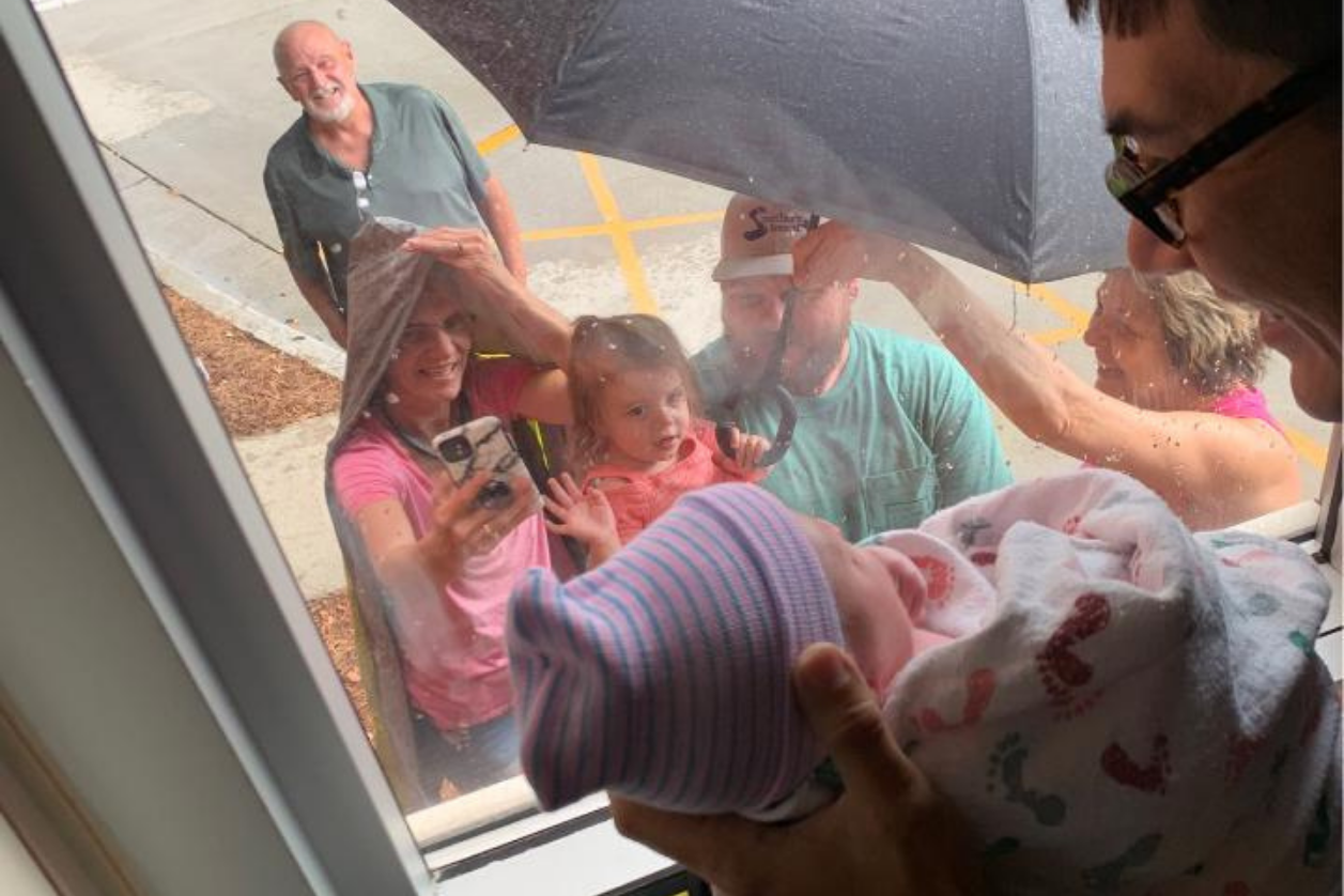 Photo of patient holding baby up to family.