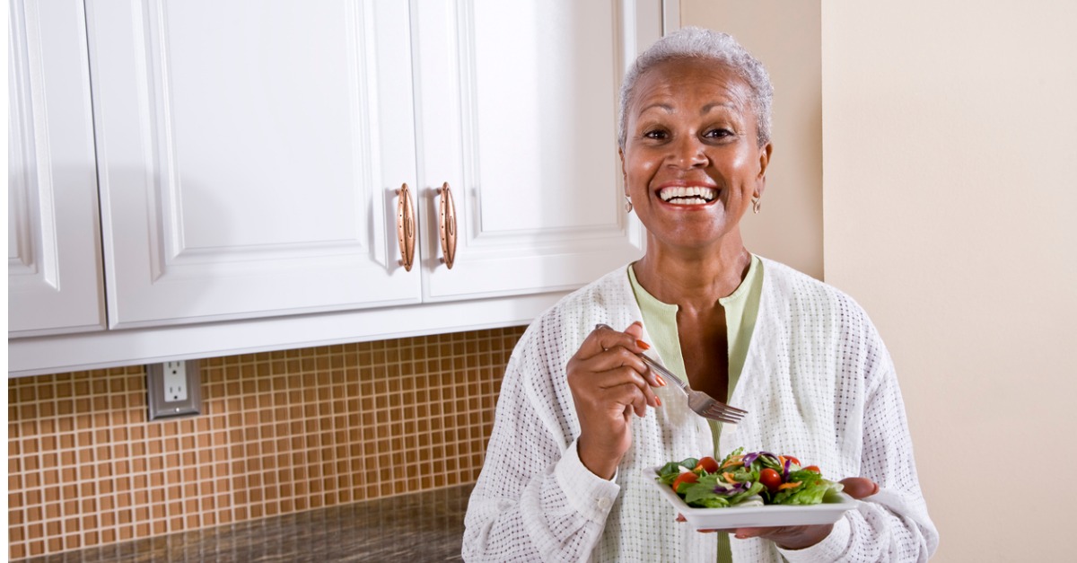 mature african american woman eating salad in kitchen