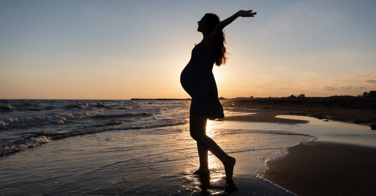 A silhouette of a pregnant woman on the beach at sunset