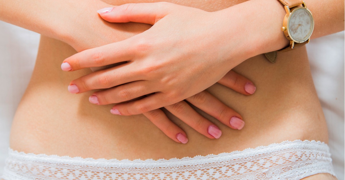 woman holding her stomach in her undergarments