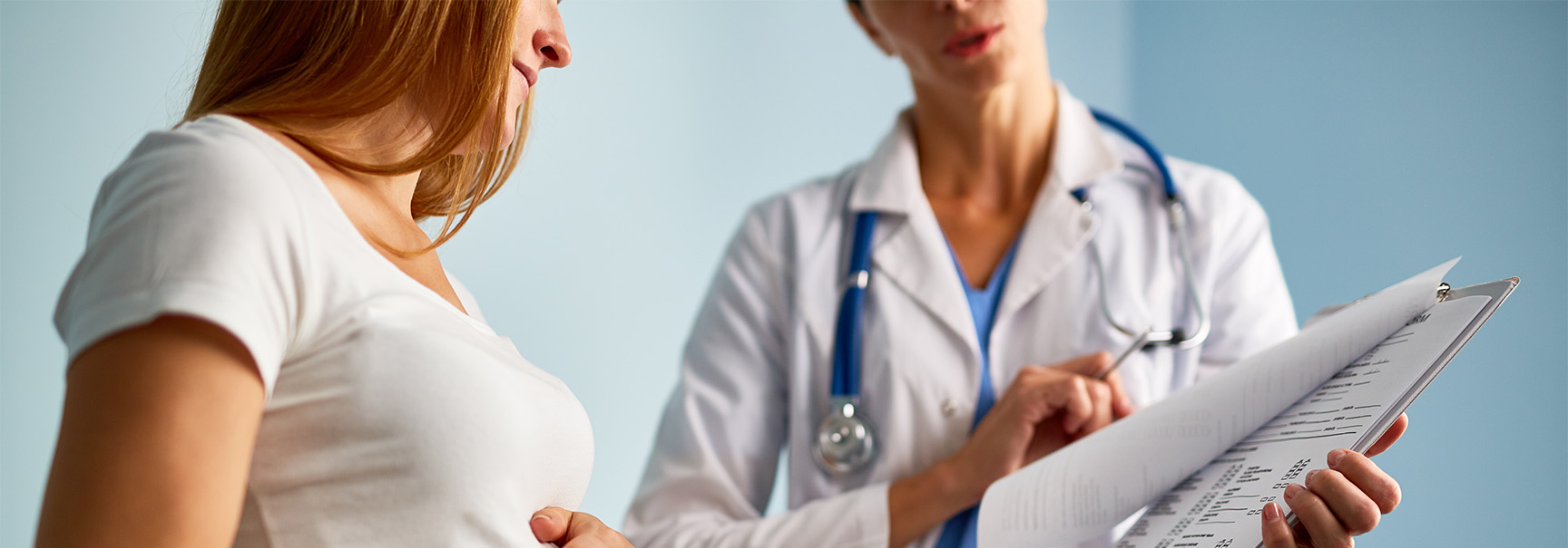 A physician going through paperwork with her pregnant client.