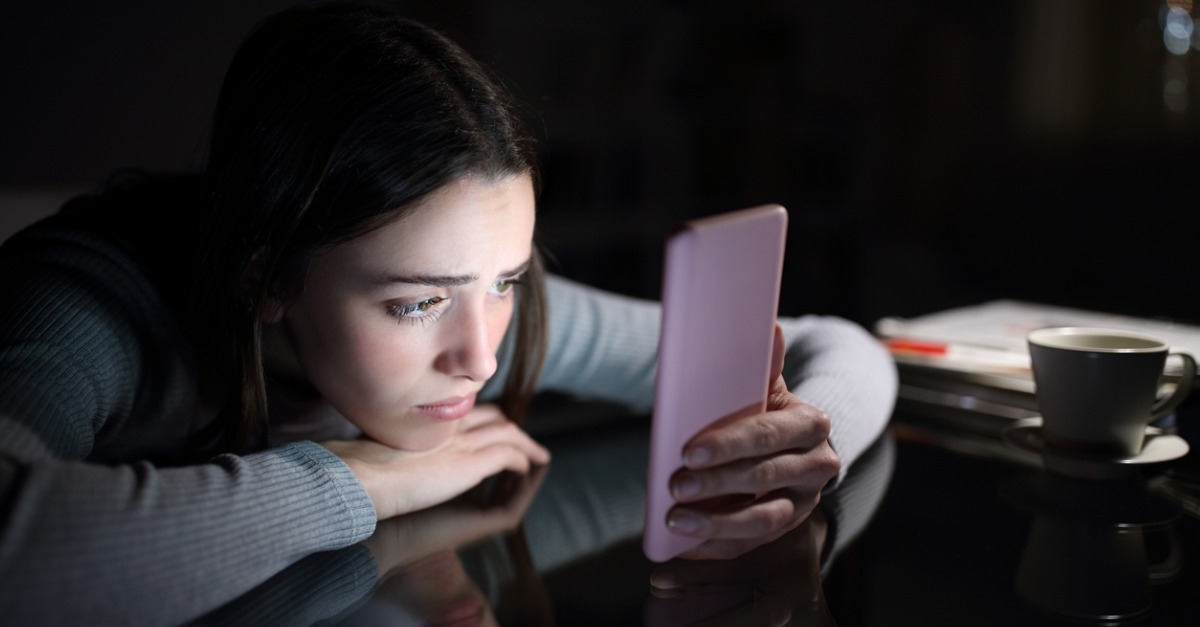 sad female checking phone content in the dark