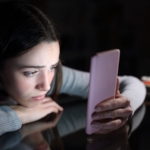 sad female checking phone content in the dark