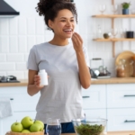 woman taking vitamins in kitchen