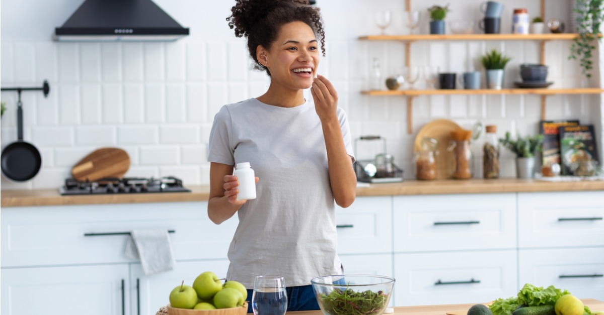 woman taking vitamins in kitchen