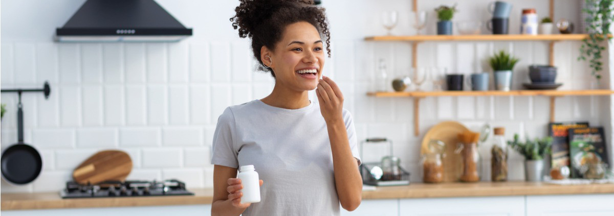 woman taking vitamins in kitchen