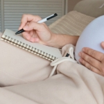 pregnant woman writing in notebook