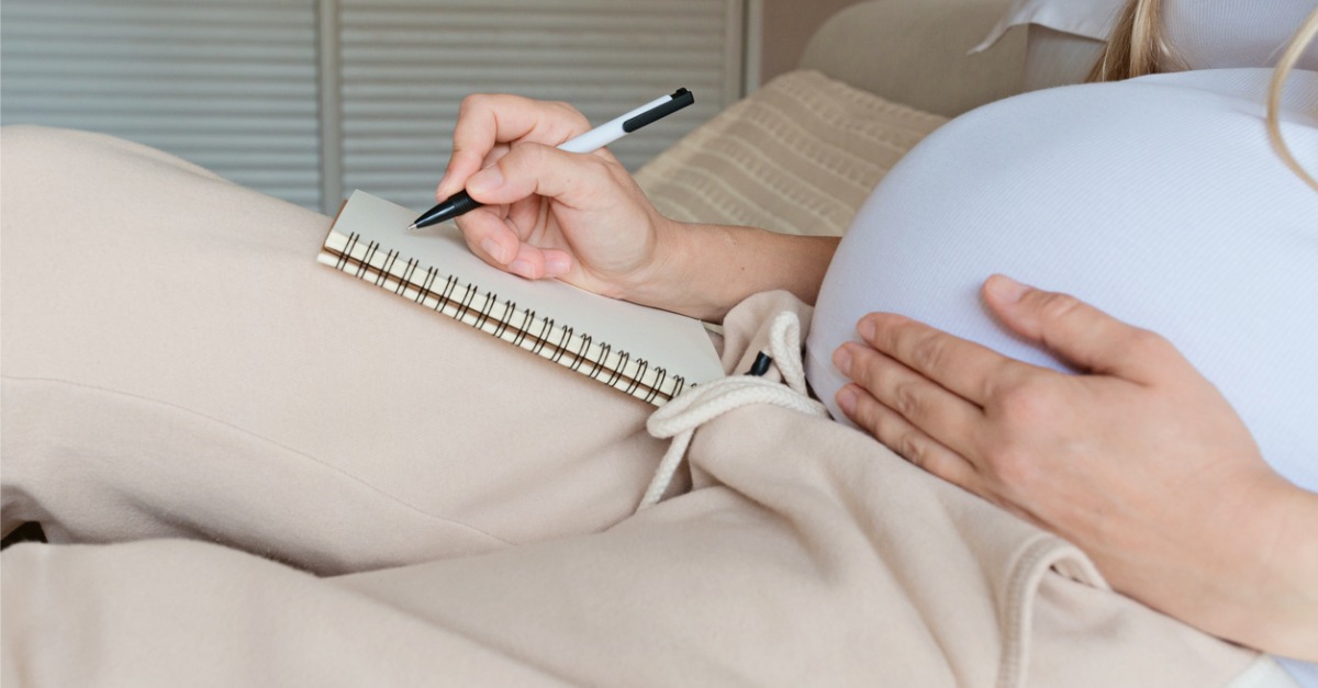 pregnant woman writing in notebook