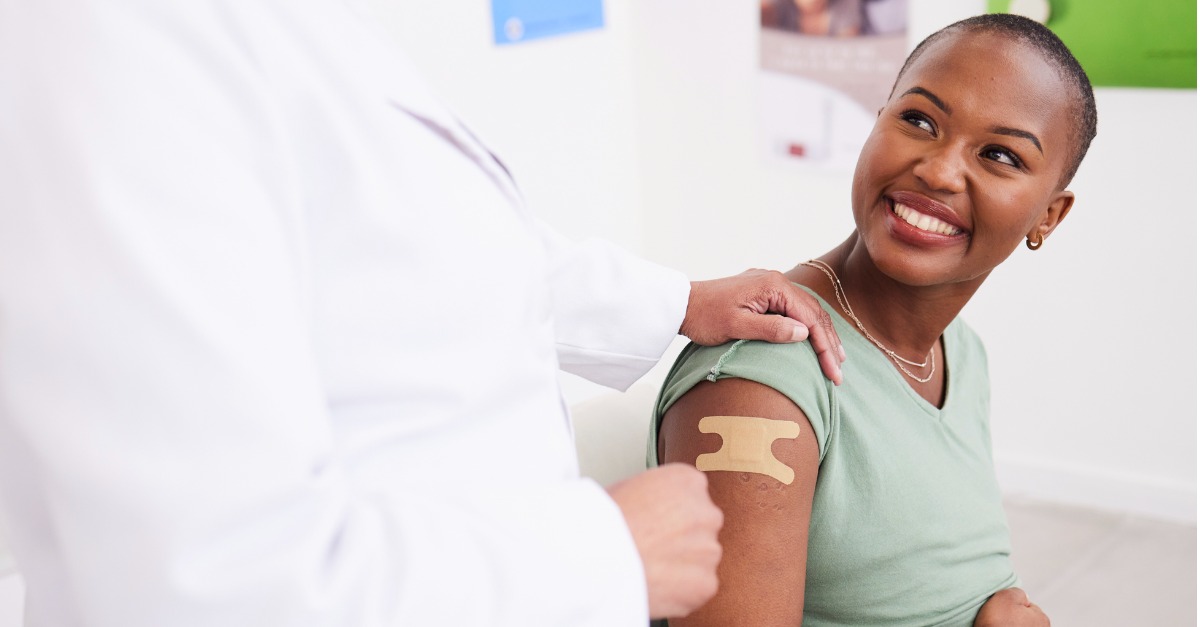 An African American lady smiling after a shot in a medical clinic.