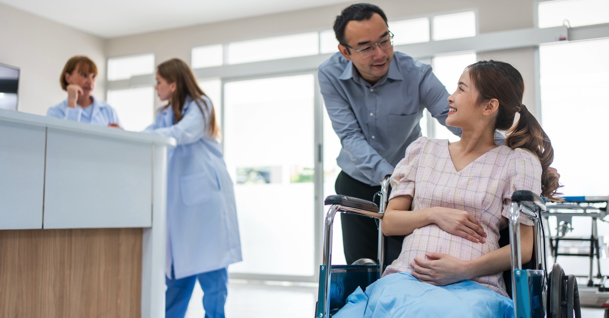 man with pregnant woman in a wheel chair at a hospital