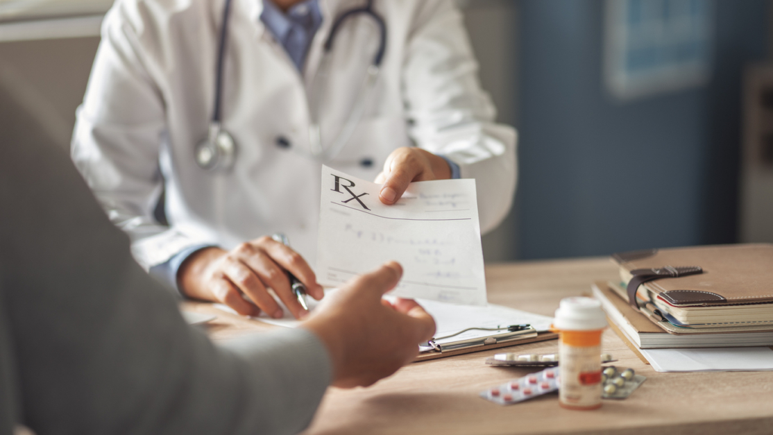 Physician handing a patient a prescription during an office visit